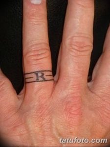Фотография татуировки на пальце в виде буквы 'R', выполненной черными чернилами. Простой и лаконичный дизайн.