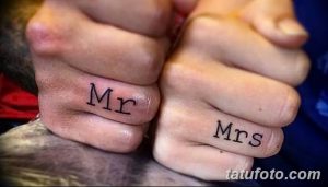 Фото тату надписей 'Mr' и 'Mrs' на безымянных пальцах пары, символизирующих брак и любовь. Простой и элегантный дизайн.