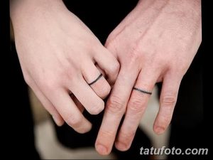 Фото парных татуировок в виде тонких черных полосок на пальцах, имитирующих обручальные кольца. Минималистичный и символичный дизайн татуировки для влюбленных.