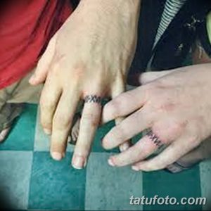 Фото тату с изображением черных колец на безымянных пальцах пары. Рисунок татуировки выполнен в минималистичном стиле.