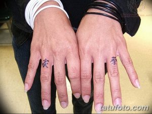 Фото тату: Два пальца с маленькими черными иероглифами, символизирующими, возможно, любовь или дружбу. Минималистичный рисунок татуировки.