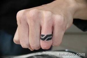 Фото тату: Черная татуировка в виде браслета на пальце руки. Простой и минималистичный рисунок татуировки.
