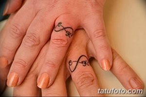 Фото парных тату на пальцах. Символ бесконечности с буквами 'e' и 'K' внутри, нанесен на пальцы пары.