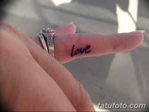 Фото минималистичной татуировки: на пальце девушки выбито слово 'Love' черным цветом, символизирующее любовь и привязанность.