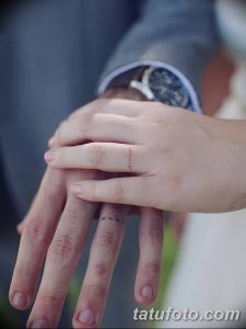Фото татуировки на пальце: тонкая, прерывистая красная линия, символизирующая связь и хрупкость отношений. Минималистичный дизайн.