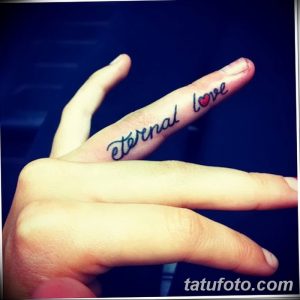 Фото тату: надпись "Eternal Love" на пальце руки. Черно-синий рисунок татуировки, каллиграфический шрифт, романтичный дизайн.