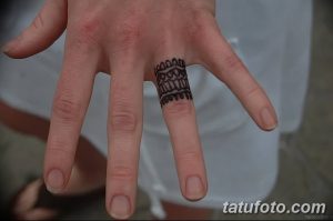 Фото татуировки на пальце в виде черного геометрического браслета. Татуировка выглядит стильно и современно, подчеркивая индивидуальность.