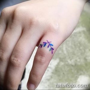 Фото тату: акварельная татуировка в виде веточки с листьями на пальце руки. Нежный и красочный рисунок.