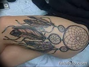 Фото черно-серой татуировки с несколькими ловцами снов и перьями на бедре. Красивый рисунок татуировки для девушек, выполненный в минималистичном стиле.