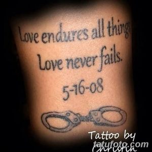 Фото татуировки на предплечье с фразой "Love endures all things, Love never fails" и изображением наручников. Черно-серый рисунок татуировки в реалистичном стиле.