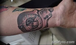 Фото татуировки карманных часов с ключом на запястье. Детализированный рисунок татуировки в стиле реализм.