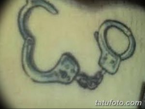 Фото простой татуировки наручников в черно-серых тонах. Минималистичный рисунок на коже.