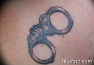 Фото простой татуировки наручников в черно-белых тонах. Минималистичный рисунок на коже.
