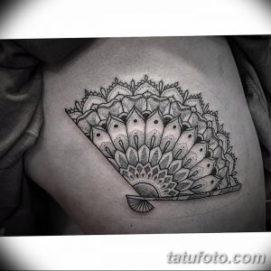 Фото тату на плече с изображением веера, выполненного в технике dotwork. Четкие линии и точечный узор.