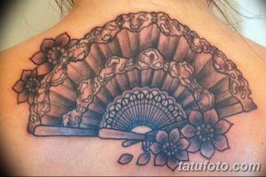 Фото тату на спине с изображением раскрытого веера, выполненного в технике blackwork. Четкие линии и геометрические узоры.