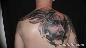 Фото тату головы козла с большими рогами на спине. Выполнена в черно-серых тонах с реалистичной детализацией.