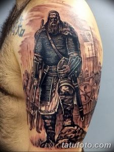 Фото тату воина в доспехах на плече. Реалистичный рисунок татуировки с использованием черного и серого цветов.