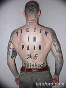 Фото татуировки на спине мужчины с надписью 'VICTIM IN PAIN A.F. SKINHEAD', выполненной готическим шрифтом.