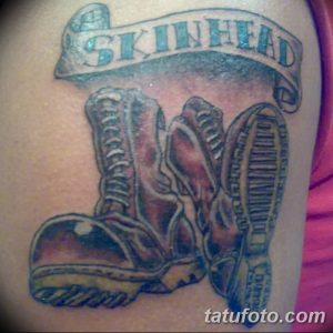 Фото тату на руке с изображением ботинок Dr. Martens и надписью "Skinhead". Черно-серый рисунок татуировки в реалистичном стиле.