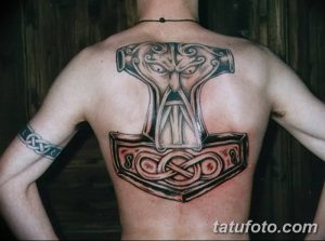 Фото татуировки молота Тора (Мьёльнира) на спине, выполненной в серо-черных тонах с использованием кельтских узоров. Детализированный рисунок татуировки.