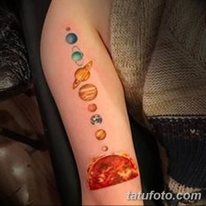 Фотография цветной татуировки на руке, изображающей Солнечную систему с ярким изображением Солнца и планетами, расположенными вдоль руки.
