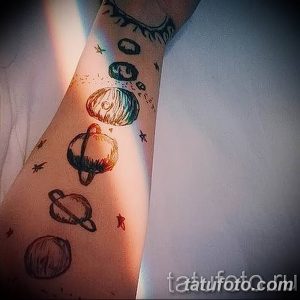 Фото тату: минималистичные планеты солнечной системы, выстроенные в ряд на предплечье. Рисунок выполнен в черно-белой гамме с добавлением небольших звезд.