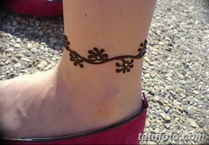 Фото тату мехенди в виде браслета на лодыжке, украшенного небольшими цветочками. Минималистичный и стильный дизайн для любителей нежных татуировок.