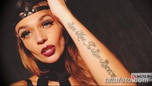Фотография девушки с татуировкой надписью на руке. Яркий макияж, стильный наряд и уверенный взгляд.