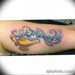 Фото тату: Цветная татуировка Джина с надписью 'Dreamer', выполненная в ярких и насыщенных цветах.