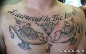 Фото тату с изображением двух волшебных ламп, бриллиантов и надписи "Diamond In The Rough", выполненное в черно-белом стиле на груди.