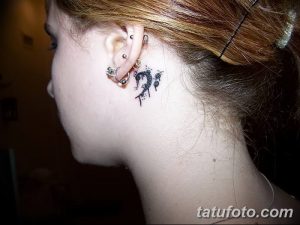 Фото тату: миниатюрный басовый ключ, расположенный за ухом. Нежный и изящный рисунок татуировки.