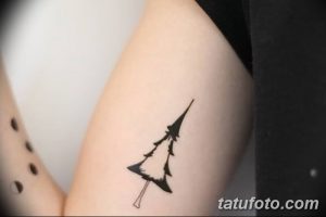 Фото простой татуировки сосны на руке. Рисунок выполнен в минималистичном стиле, с использованием черных линий.