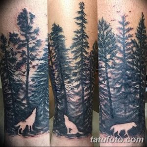 Фото тату с изображением леса и волка на руке, выполненной в технике blackwork. Рисунок включает в себя плотные черные заливки и минимальное количество деталей.