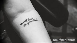 Фото тату надписи 'nevertheless, she persisted' выполненной тонкой линией на запястье, в минималистичном стиле.