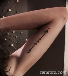 Фото тату: черная стрела на предплечье. Минималистичный рисунок татуировки, выполненный тонкими линиями.