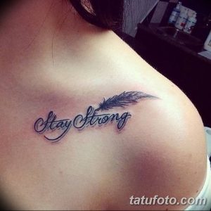 Фото тату: небольшая татуировка надписью "Stay Strong" и изображением пера на ключице. Черно-белый рисунок в каллиграфическом стиле.