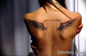 Фото тату на спине с изображением двух крыльев и надписью 'Embrace Your Dreams', выполненное в черно-белой графике.