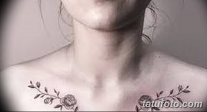 Фото тату: нежные цветочные ветви с бутонами роз под ключицами у девушки. Минималистичный рисунок татуировки в черно-серых тонах.