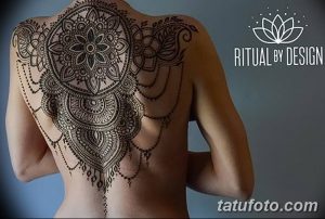 Фото тату хной: сложный узор на спине девушки, сочетающий элементы мандалы, растительные мотивы и ниспадающие линии, выполненный черной хной.