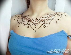 Фото тату хной на ключицах и верхней части груди. Деликатный узор из завитков и точек, украшенный мелкими стразами.