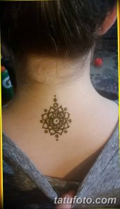 Фото тату: небольшая и изящная татуировка мехенди на затылке, с круглым цветочным узором. Идеально подходит для тех, кто ищет минималистичные идеи.