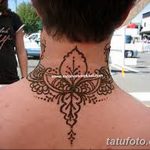 Фото тату мехенди на затылке. Симметричный рисунок с цветочными элементами и геометрическими узорами, выполненный в технике росписи хной.