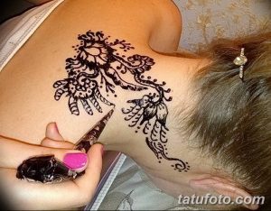 Фото процесса нанесения тату мехенди на плечо. Мастер наносит рисунок с помощью конуса с хной, демонстрируя детализацию и мастерство.