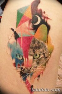 Фото тату акварельного кота с полумесяцем на плече. Яркие цвета, брызги краски, необычный стиль.