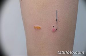 Фото тату рыбы и крюка на ноге. Небольшой и минималистичный рисунок татуировки, выполненный в ярких цветах, подходит для летнего образа.