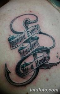 Фото тату крючка с надписью 'Behind Every Leader is a Hook'. Черно-белый рисунок на плече, символизирующий хитрость и лидерство.
