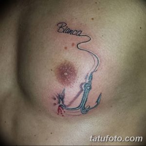 Фото татуировки на груди с изображением рыболовного крючка и надписью "Bianca". Черно-серый рисунок с добавлением красных акцентов. Персонализированный и оригинальный дизайн.