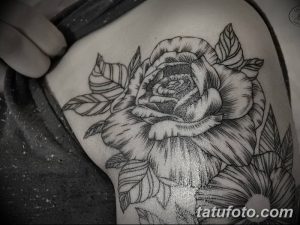 Фотография татуировки на плече, изображающей большую розу с листьями, выполненную в стиле blackwork с использованием черных линий и точек.