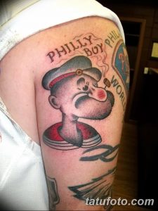 Фото тату на плече с изображением Поппи в кепке и надписью 'Philly Boy'. Детализированный рисунок и яркая цветовая палитра.