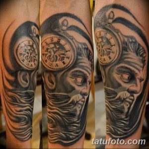 Фото тату: реалистичное изображение часов с человеческим лицом на предплечье, выполненное в черно-серых тонах с детализированными тенями и текстурами.